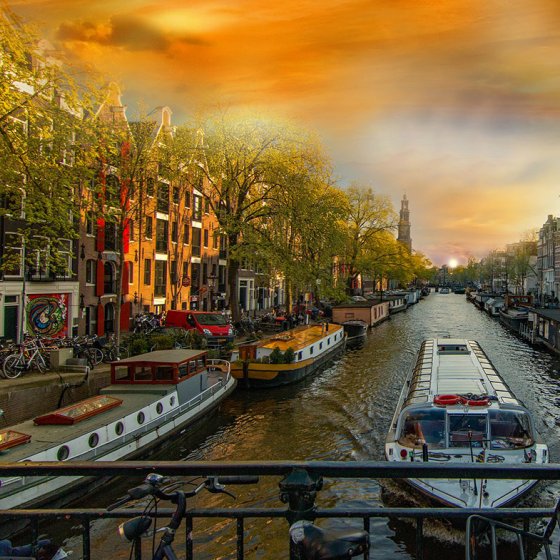 Industrial waterfront at NDSM Wharf with a vibrant sunset in the background.