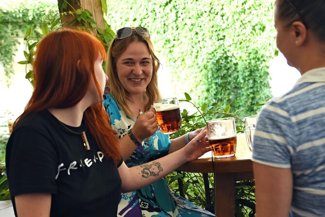 A couple smiling and clinking beer mugs together in a lively Prague beer hall.