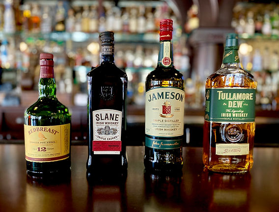 Variety of Irish whiskeys and beers displayed on a pub bar.