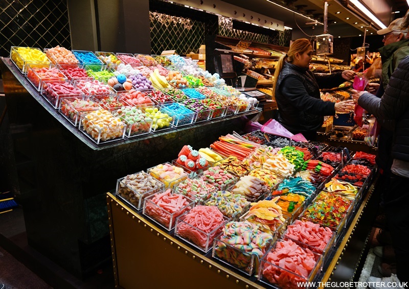 A bustling view of the colorful fruit and food stalls inside La Boqueria Market