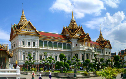 The ornate and golden spires of the Grand Palace complex in Bangkok, Thailand, with Wat Phra Kaew visible.
