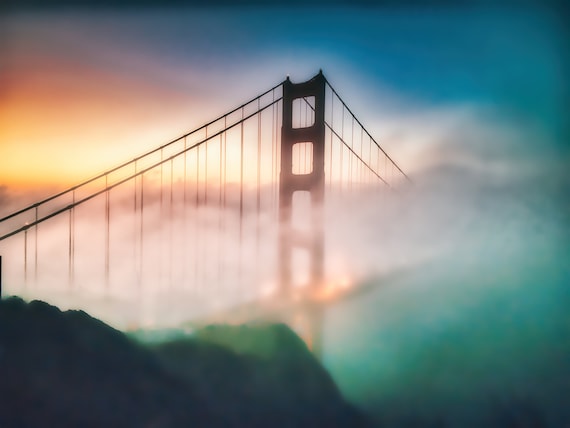 The majestic Golden Gate Bridge partially obscured by dramatic rolling fog on a cloudy day.