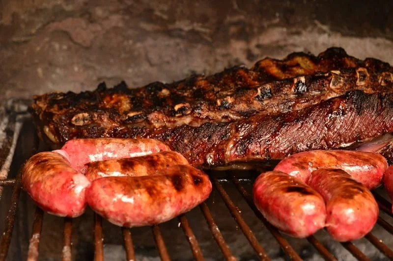A close-up of perfectly grilled Argentine steaks sizzling on a parrilla grill.